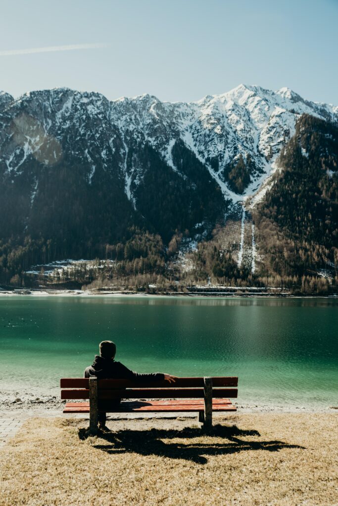 Les résolutions, homme regardant sur un banc un paysage de montagne avec un lac 